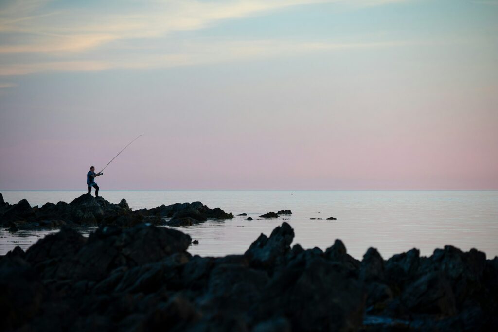 silhoutte of a man fishin on calm sea silhoutte of a man fishin on calm sea